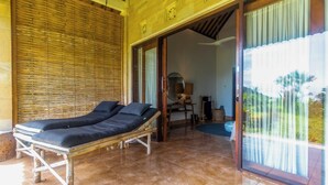 Una habitación con cama de madera, un espejo y vistas al exterior con vegetación.