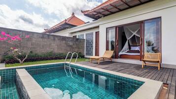 Una piscina con muelle de madera, una cama con dosel y un techo de tejas tradicionales.