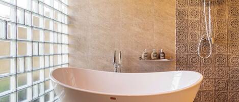 Une salle de bain moderne avec une baignoire sur pieds, une douche et une fenêtre à motifs géométriques.