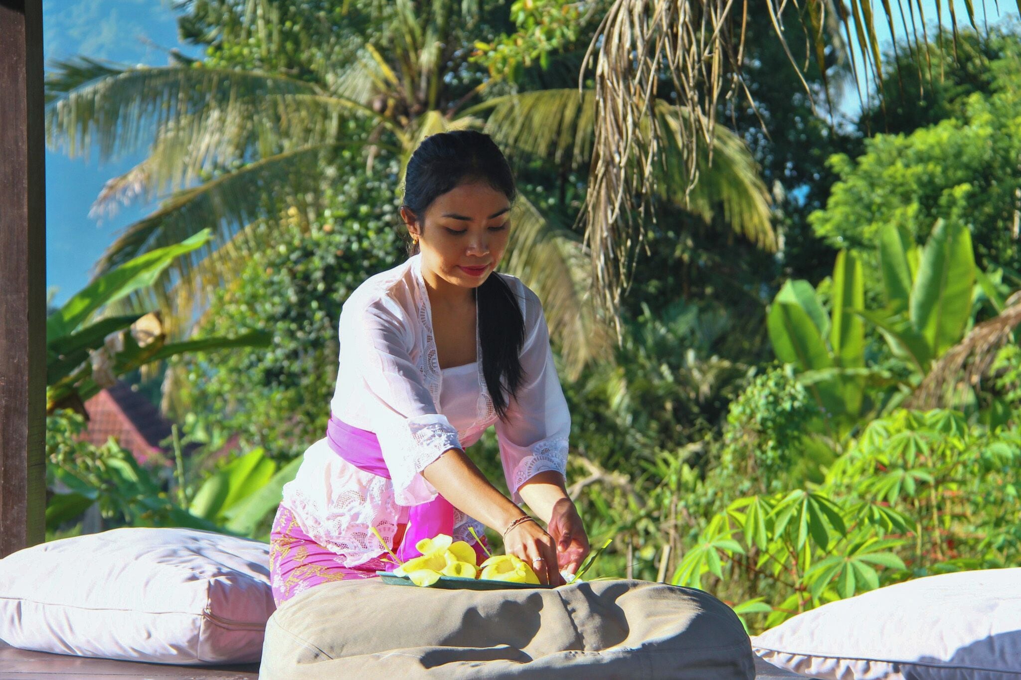 A person sitting on a bench outdoors with greenery in the background.