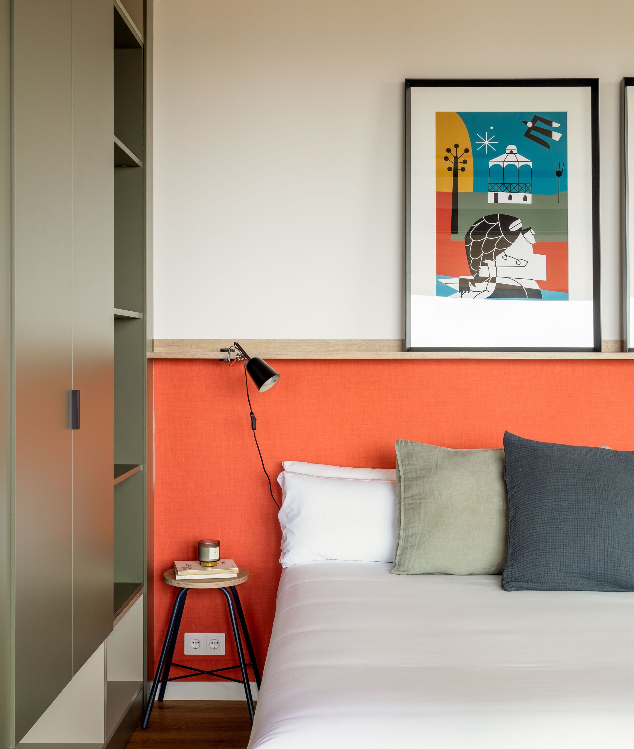 Quarto com cama, mesa de cabeceira, luminária e um quadro na parede.
