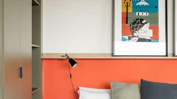 Quarto com cama, mesa de cabeceira, luminária e um quadro na parede.