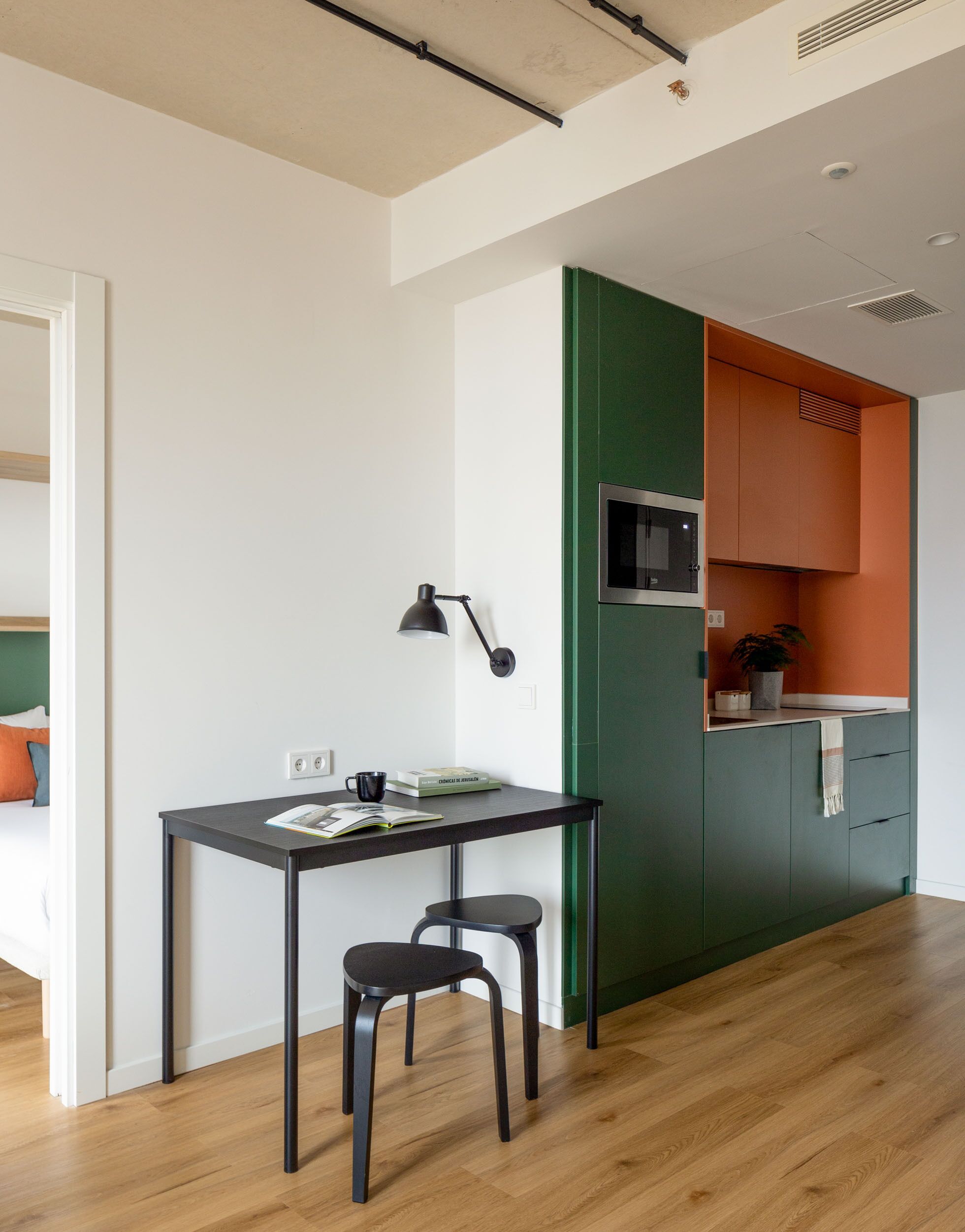 A modern kitchen with a green accent wall, a small island with a sink, and a dining area with a table and chairs.