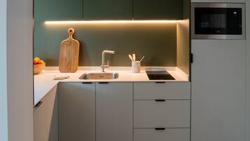 A modern kitchen with a built-in microwave, a sink, and a wooden cutting board.
