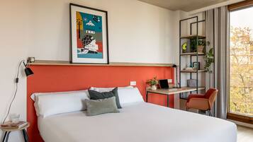 A modern bedroom with a large bed, a desk, a chair, and a bookshelf.