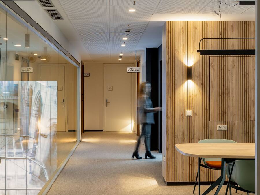 A modern office space with glass partitions, a wooden panel wall, and a sign for 'The Cinema'.