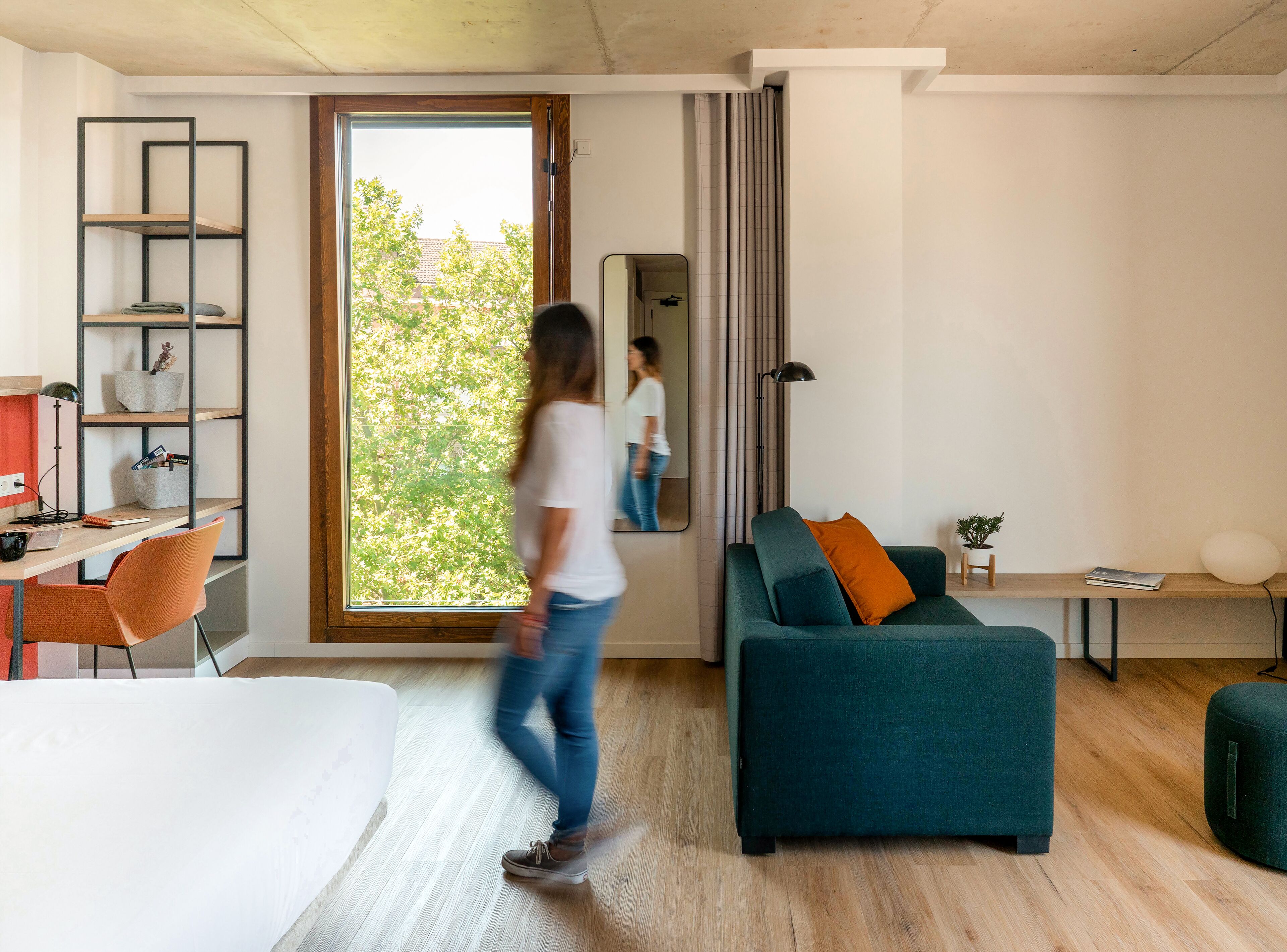Ein modernes Wohnzimmer mit großem Fenster, einer Couch, einem Schreibtisch und einem Sessel.