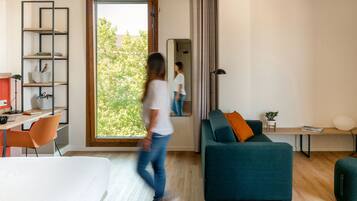Ein modernes Wohnzimmer mit großem Fenster, einer Couch, einem Schreibtisch und einem Sessel.
