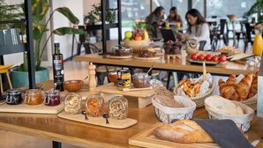 A café with a variety of food items and condiments on display, including jars of honey, jams, and nuts, as well as bread and pastries. - Aparthotel Kora Green City  (Vitoria-Gasteiz)