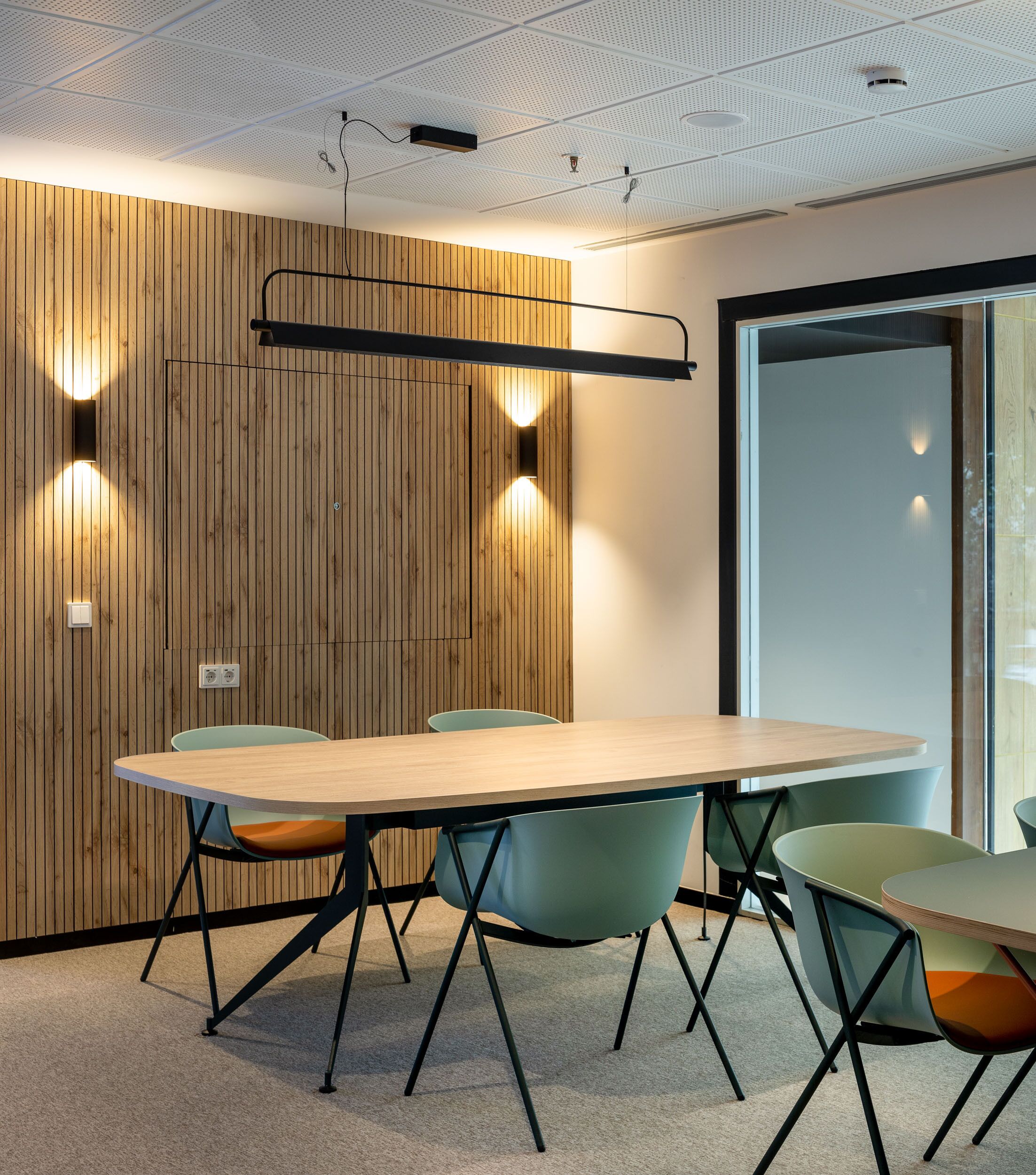 A conference room with a wooden panel wall, a large table, and four chairs.