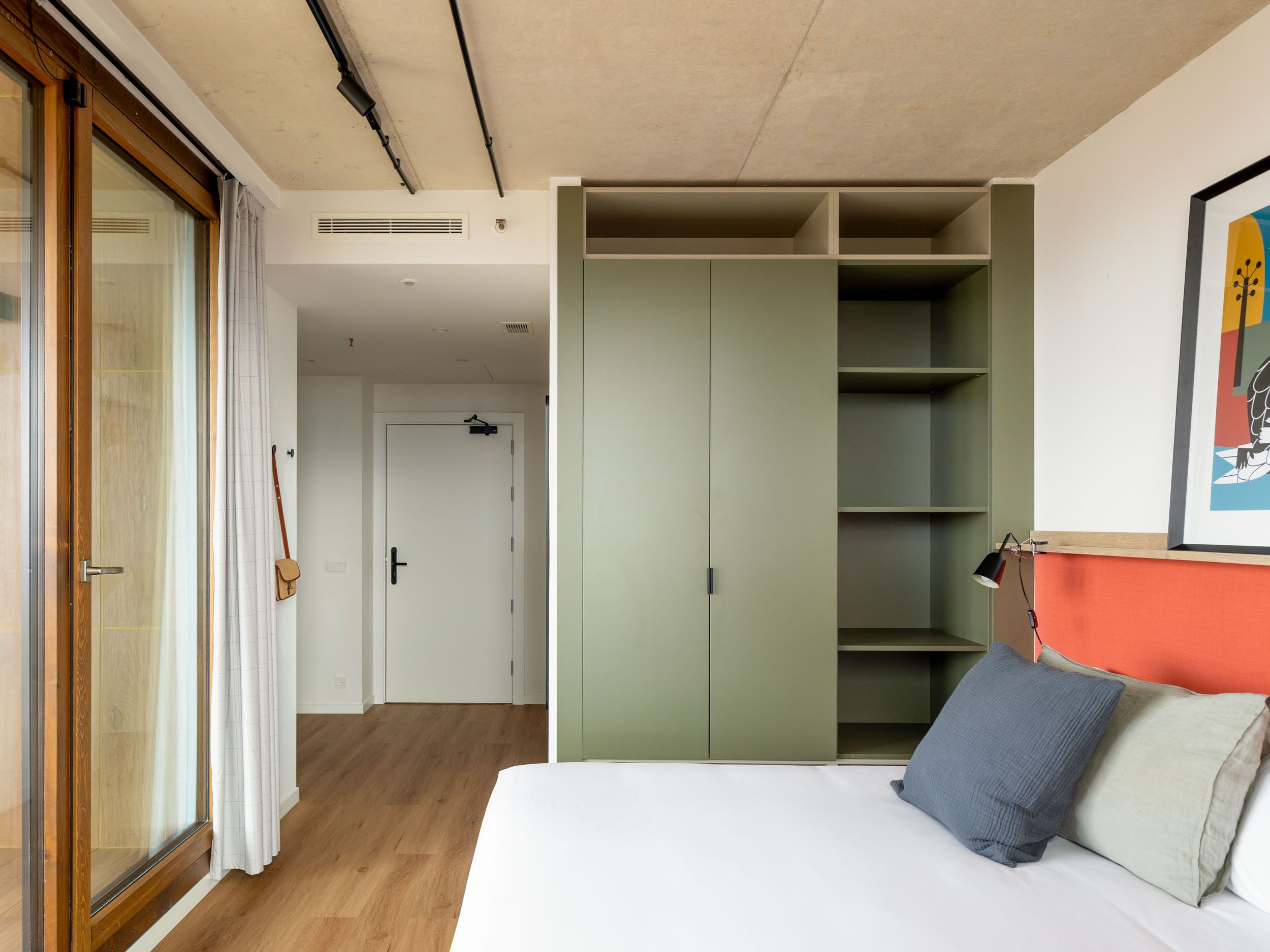 Un dormitorio con cama, armario, puerta y ventana.