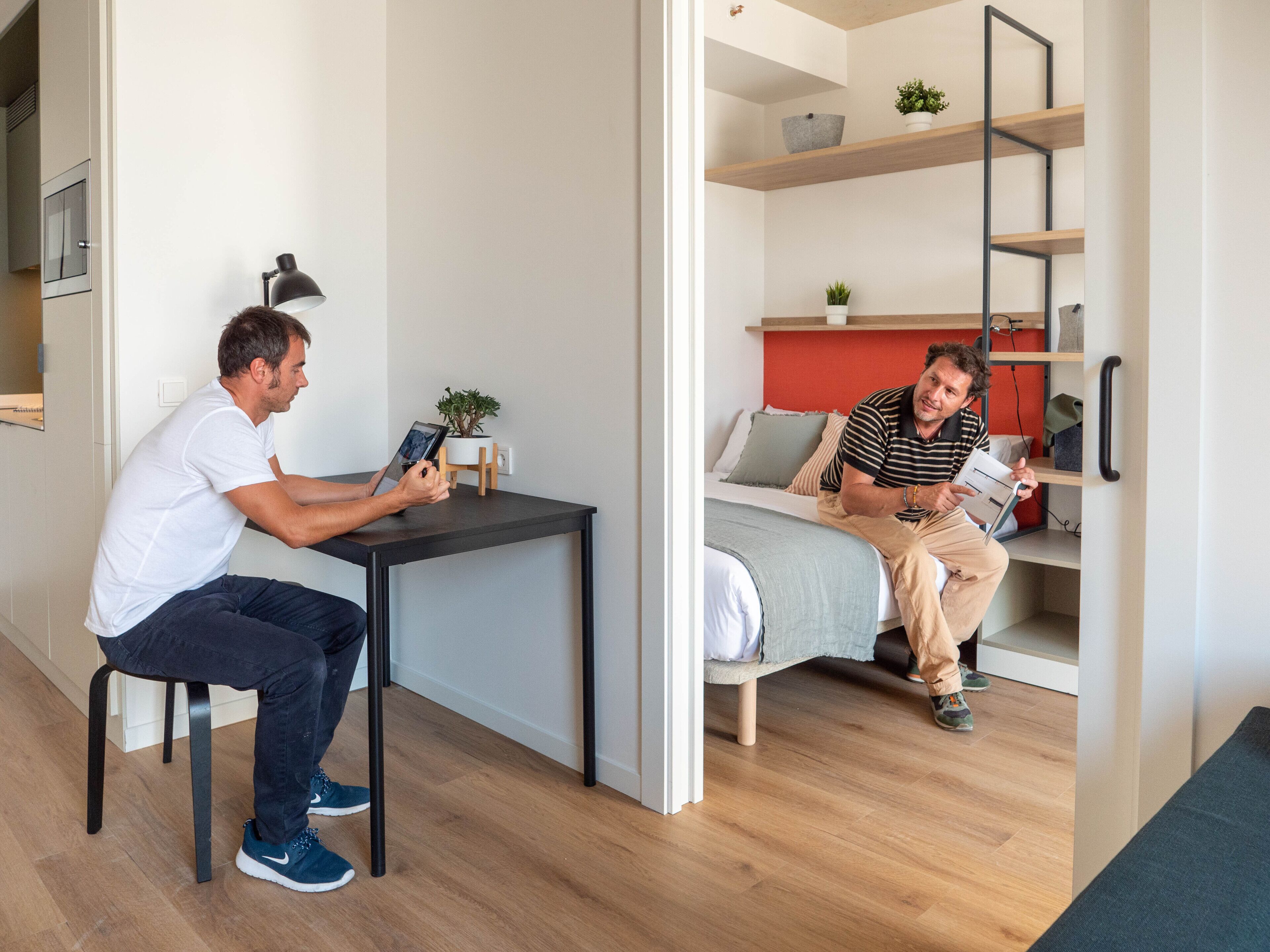 Un espacio habitable moderno y compacto con cama, una mesita y un escritorio.