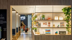 A modern interior with a reception desk, shelves with books and decorative items, and a sign indicating 'SALIDA' (exit). - Aparthotel Kora Green City  (Vitoria-Gasteiz)