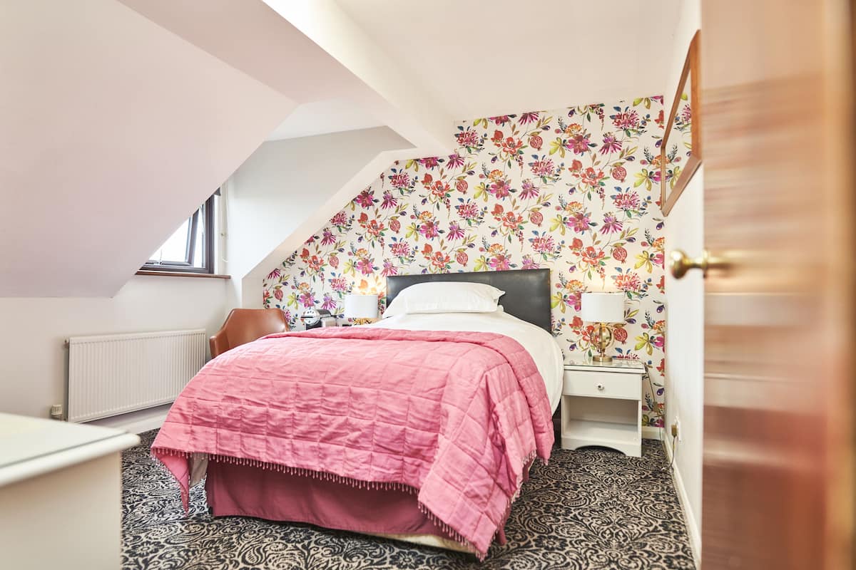 A bedroom with a bed, a nightstand, a lamp, and a radiator.