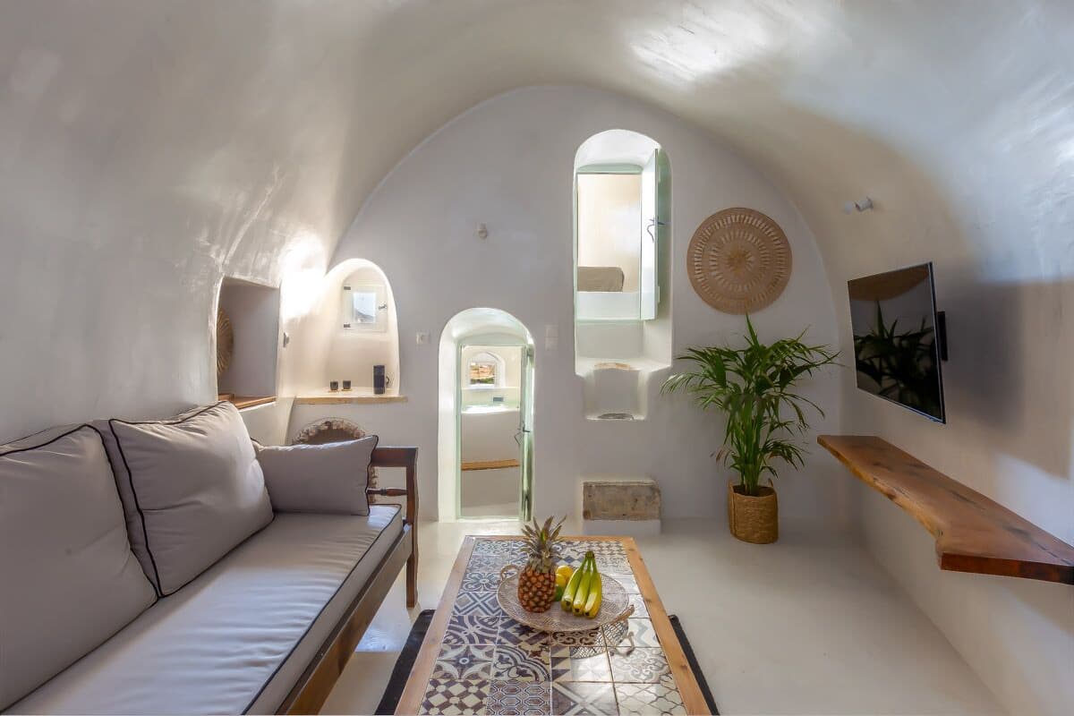 A cozy interior with a sofa, a table with fruits, a potted plant, and a wooden shelf.