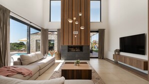 Ein modernes Wohnzimmer mit einer Couch, einem Couchtisch, einem Kamin und einem an der Wand befestigten Fernseher.