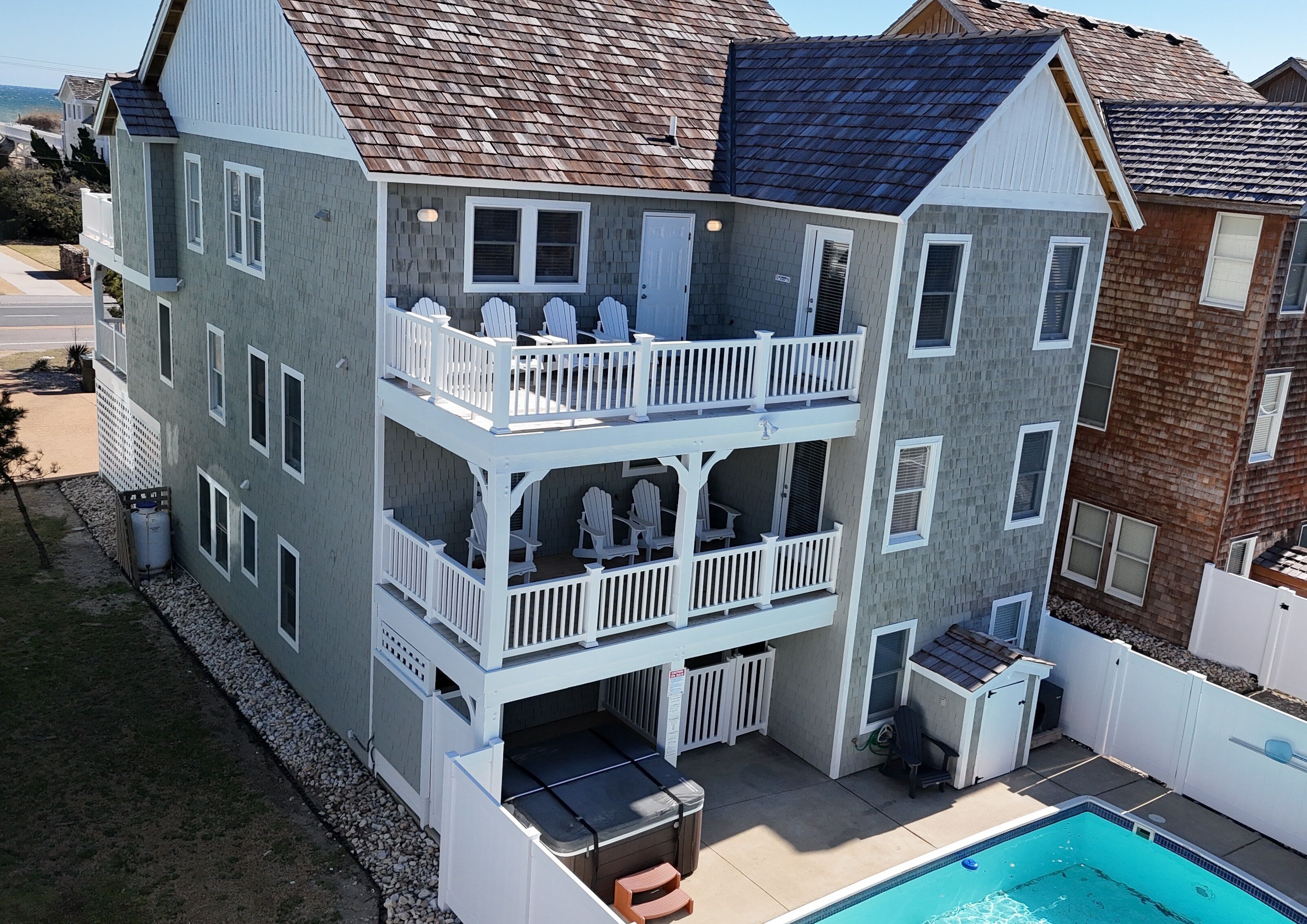 A multi-story residential building with a balcony on the second floor, a pool, and a garage.