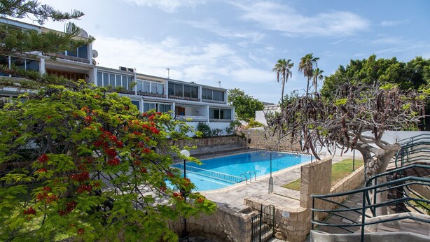 Ein Swimmingpool, umgeben von Steinmauern, mit einer Treppe, die zum Pool hinabführt.