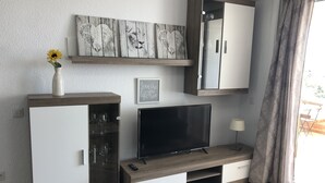 Ein modernes Wohnzimmer mit Fernseher, Schränken und einer Vase mit einer Sonnenblume.