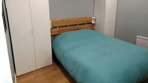 Ein Schlafzimmer mit Bett, Holzboden, grauen Wänden und weißen Schränken.
