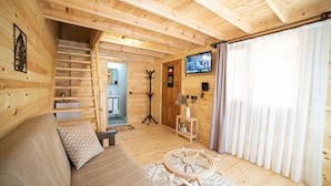 En inredning med träpanel, en soffa, ett litet bord, en tv och en trappa som leder upp till ett övre plan.