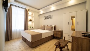 Ein modernes Schlafzimmer mit einem großen Bett, Nachttischen, einem Holztisch und einem Kleiderschrank.