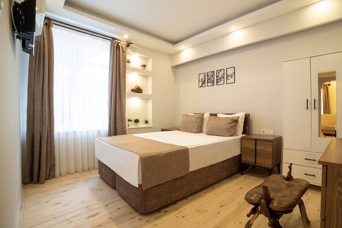Un dormitorio moderno con una cama grande, mesitas de noche, un escritorio de madera y un armario.