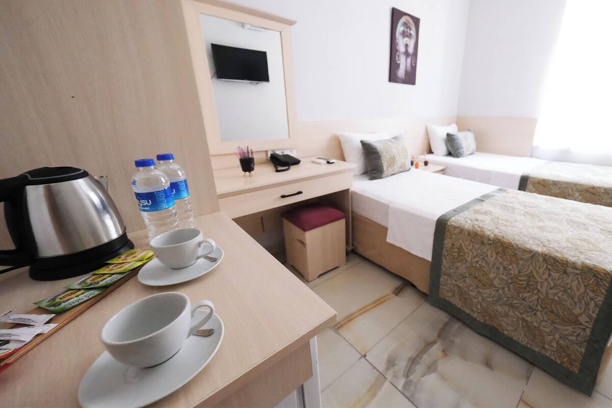 Una habitación de hotel con escritorio, dos camas, televisor y ventana.