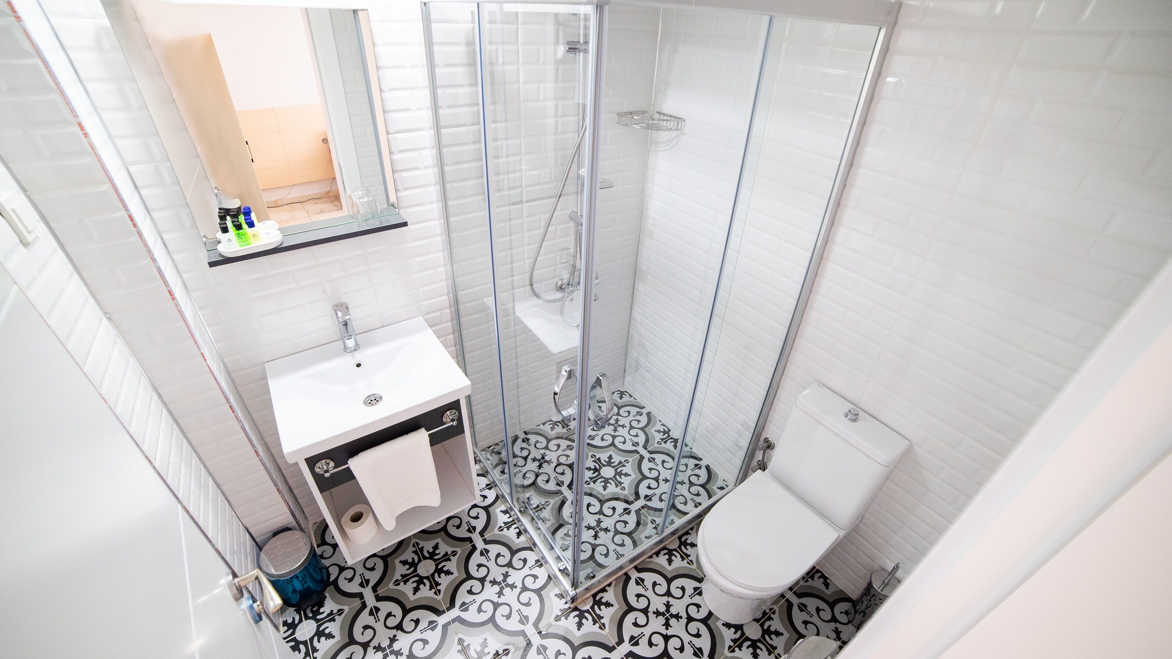 Un baño con ducha envuelta en vidrio, un lavamanos blanco y un inodoro.
