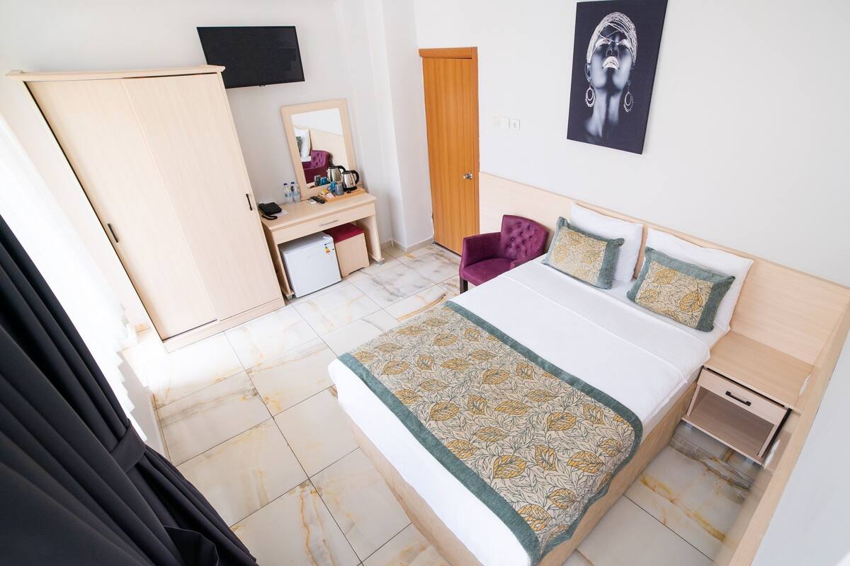 Un dormitorio con cama, escritorio, armario y espejo.