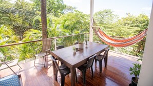 Een houten terras met een tafel, stoelen, een hangmat en potplanten.