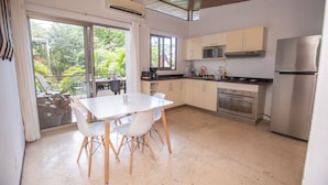 Een moderne keuken met een eethoek, grote ramen en uitzicht op groen.