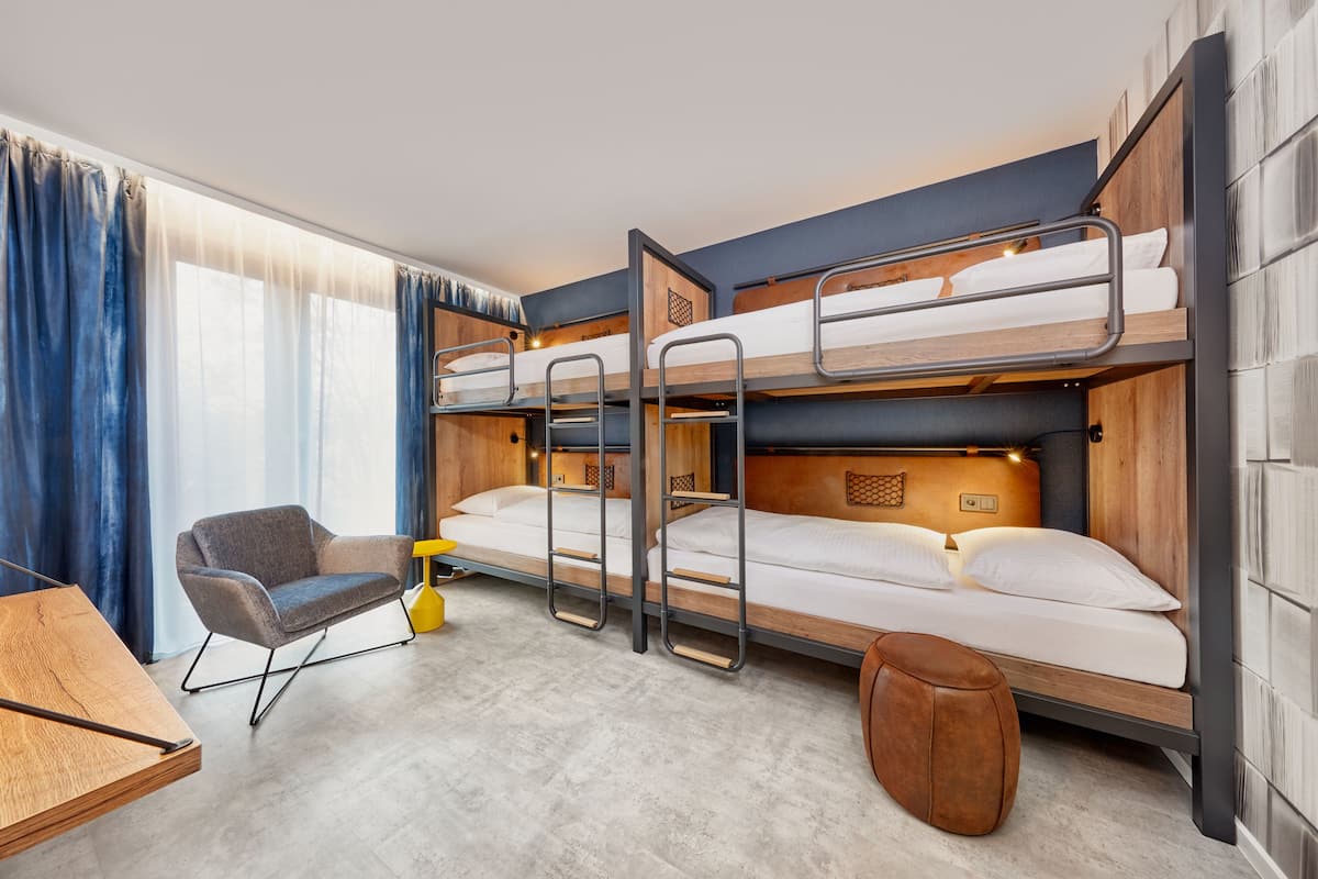A bunk bed room with a desk, chair, and ottoman.