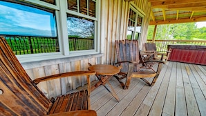A wooden deck with a covered area, wooden chairs, and a table. - Panoramic Point Cabin - Beautiful Mountain Retreat for Families (Ohiopyle)