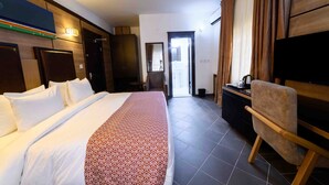 A hotel room with a large bed, a flat-screen TV, a desk with a chair, and a wardrobe. - Alpha-Plus Apartments 91 Utako (Abuja)