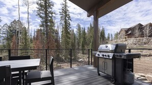 An outdoor patio with a grill, wooden deck, and a view of a forested area. - Home Across from Purg - Hot Tub, Ping Pong, Foosball, AC, Multiple Decks (Durango)