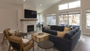 A spacious living room with a fireplace, a large sofa, a coffee table, and a TV mounted on the wall. - Home Across from Purg - Hot Tub, Ping Pong, Foosball, AC, Multiple Decks (Durango)