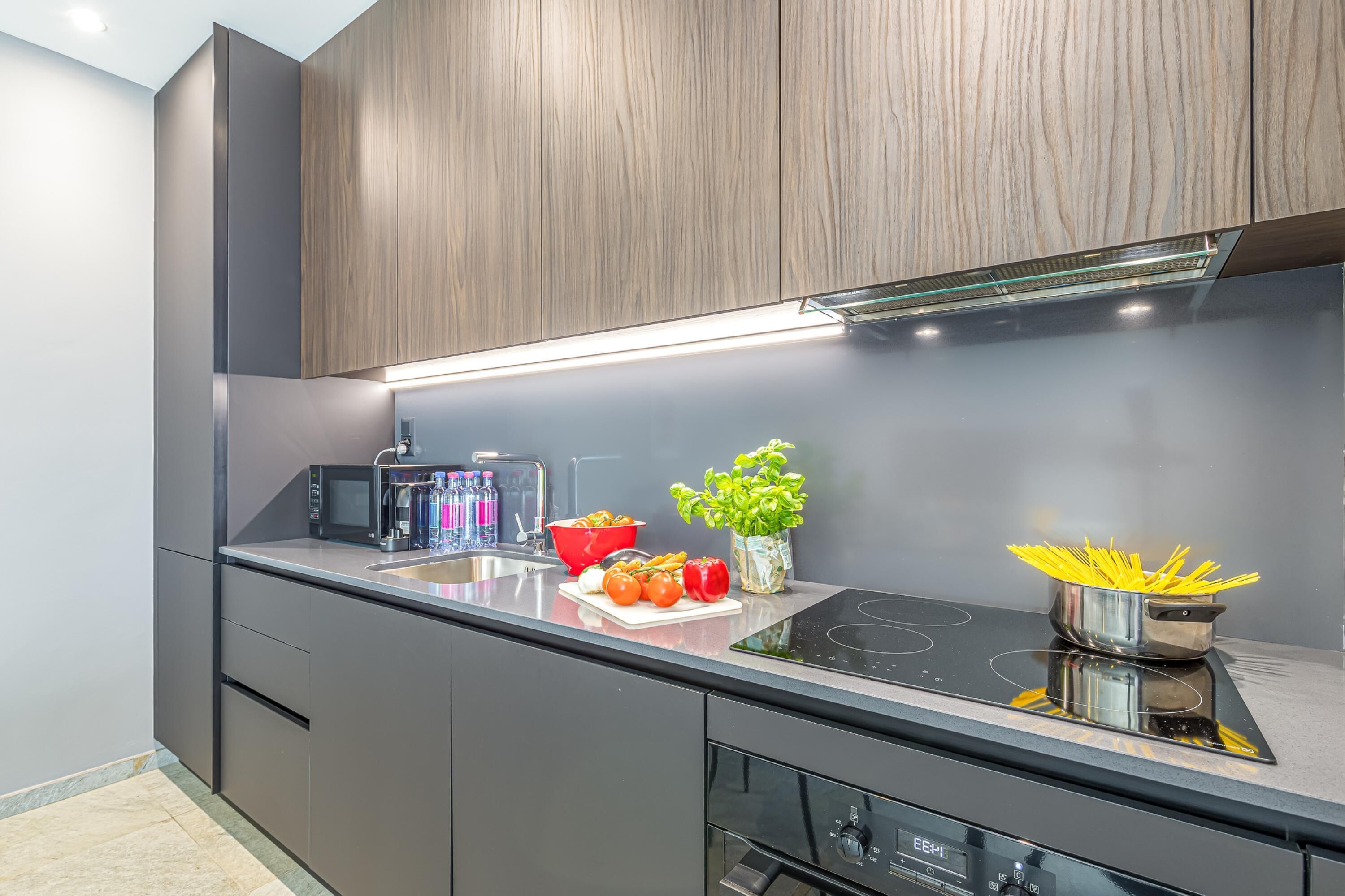 A modern kitchen with dark cabinetry, a black countertop, and a stainless steel stove.