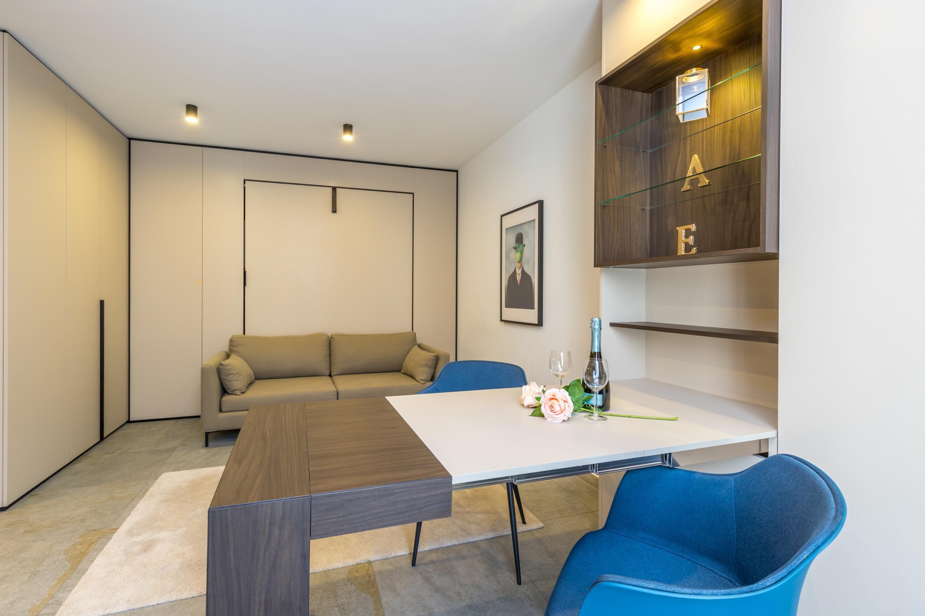 A modern living room with a sofa, a dining table, and blue chairs.