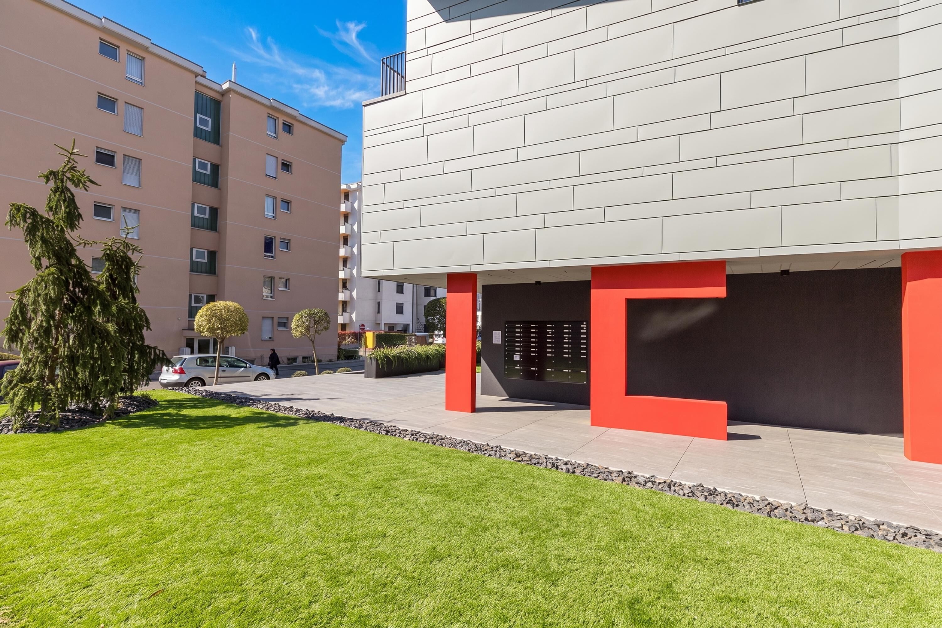 Un bâtiment moderne doté d’un toit plat, d’une allée pavée et d’une pelouse bien entretenue.