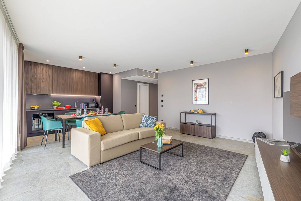 A modern living room with a sofa, coffee table, and a kitchen in the background.