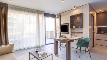 A modern living room with a sofa, coffee table, TV, and a dining area with chairs.