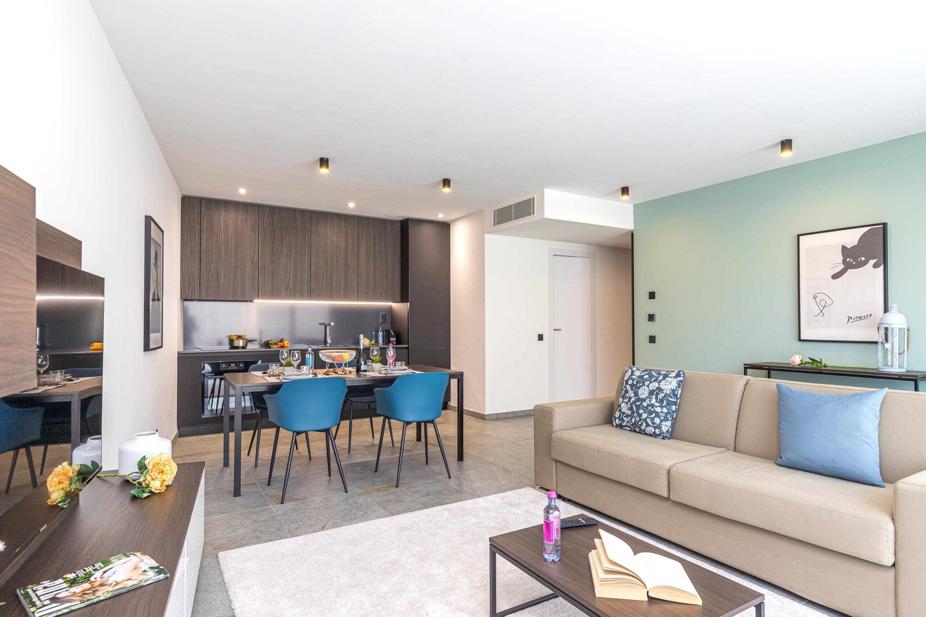 A modern living room with a sofa, coffee table, and a dining area with chairs and a table.