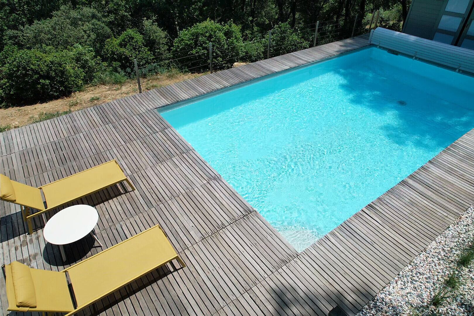 A rectangular swimming pool with a wooden deck surrounding it.