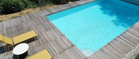 A rectangular swimming pool with a wooden deck surrounding it.