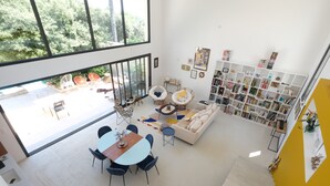 Un salón amplio con un gran ventanal, una mesa de comedor y una estantería.