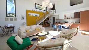 Un amplio salón con techo alto, una escalera y una zona de cocina.