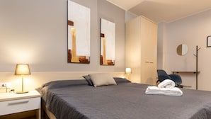Une chambre d’hôtel moderne avec un grand lit, deux lampes de chevet, une armoire et une chaise.