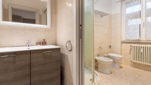 Une salle de bain moderne dotée d’une douche à parois de verre, d’un meuble-lavabo à deux vasques et de deux toilettes.