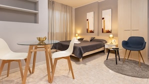 Une chambre à coucher moderne comprenant un lit, des tables de chevet, un bureau avec des chaises et une armoire.